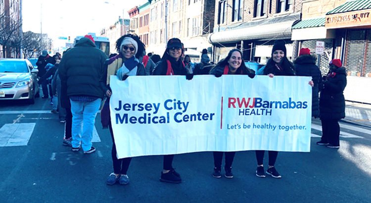 RWJBarnabas Jersey City Medical Center employees holding a Jersey City Medical Center sign for the AIDS walk.