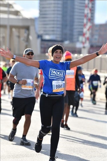 Runner smiling and throwing her hands up in the air.