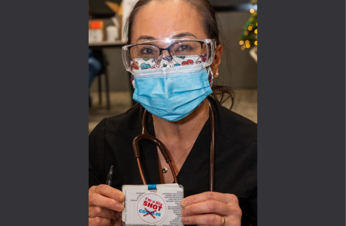 Female healthcare worker holding a I'm a Big Shot sticker.