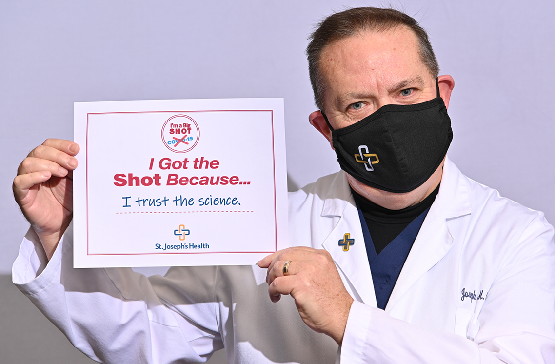 Male healthcare worker holding a I'm Got the Shot sign.